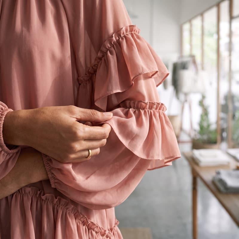 An extreme close-up of the blouse's tiered sleeve, showing the sheer chiffon, the gathered ruffles and the rolled hem.